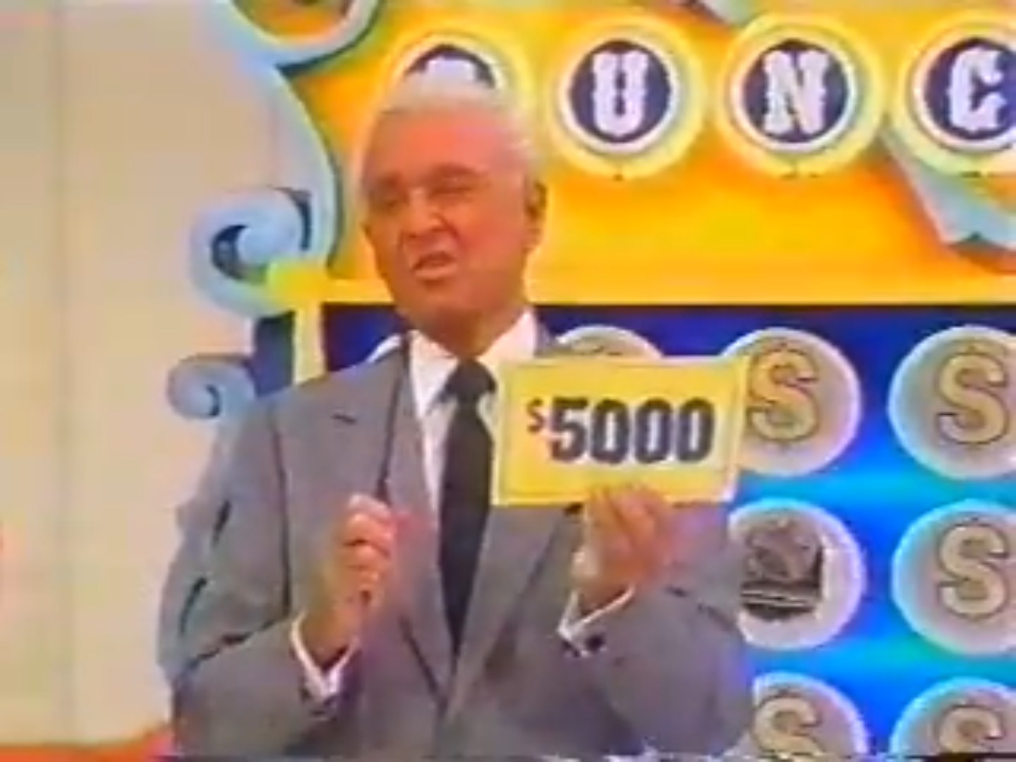 A host holding a 00 prize sign during the game show 'Punch a Bunch' with colorful graphics in the background.