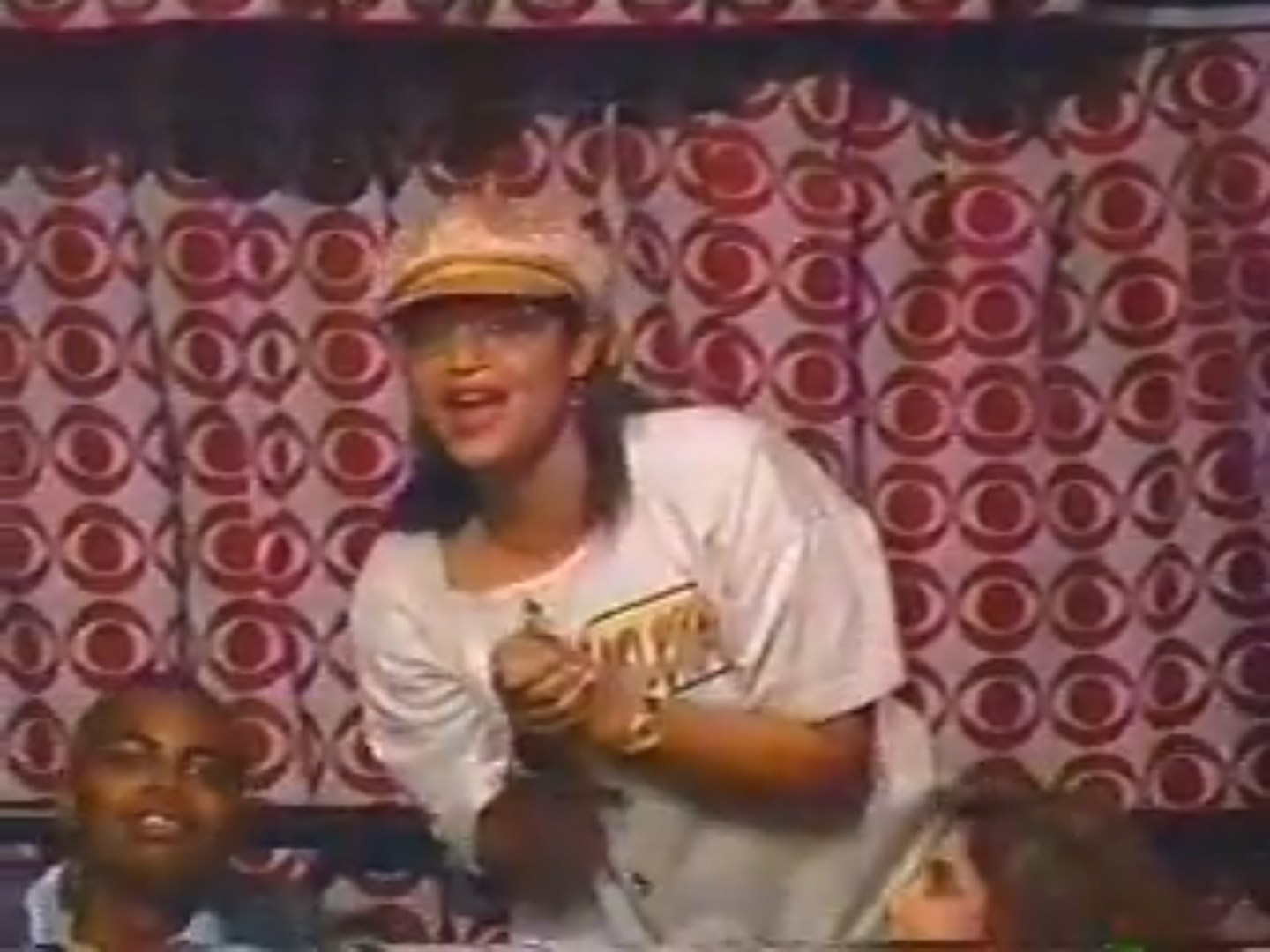A contestant in a Price is Right episode enthusiastically celebrating with a group of audience members, set against a vibrant patterned backdrop.