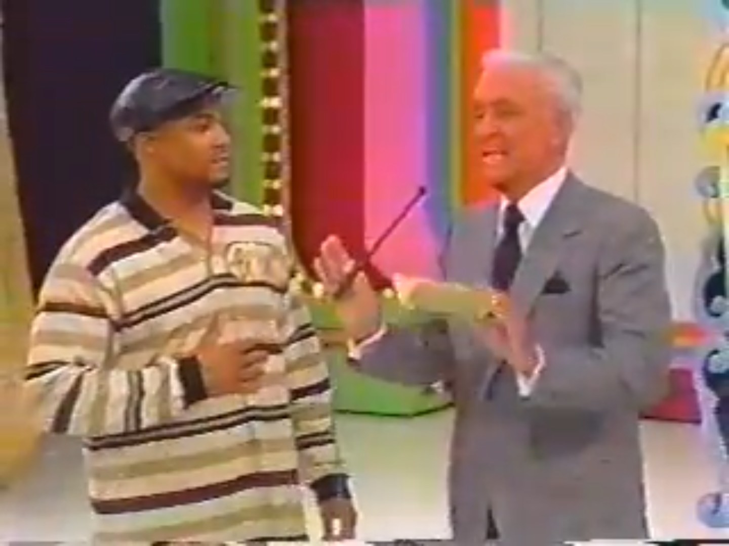 A contestant on 'The Price is Right' stands next to the host, who is holding a microphone and engaging with the audience, set against a colorful game show backdrop.