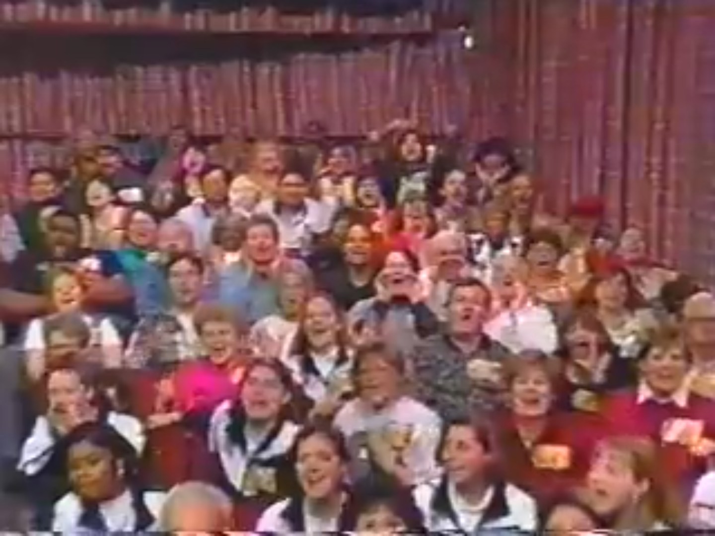 A lively audience cheering enthusiastically while participating in a game show.