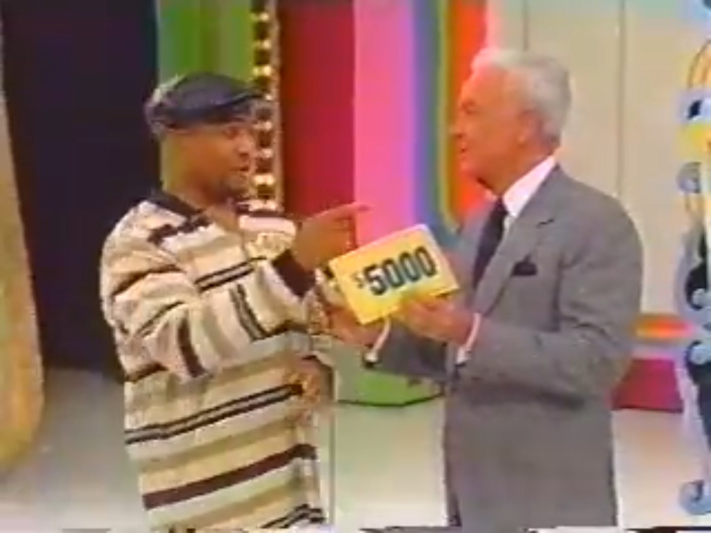 A contestant on The Price is Right holds a card displaying ,000 while engaging with the host, Bob Barker, against a colorful game show backdrop.