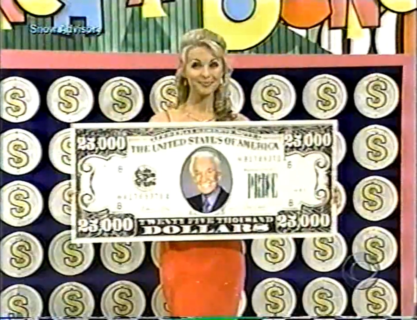 A model on The Price is Right proudly holds a large novelty check displaying ,000, with a colorful game backdrop behind her.