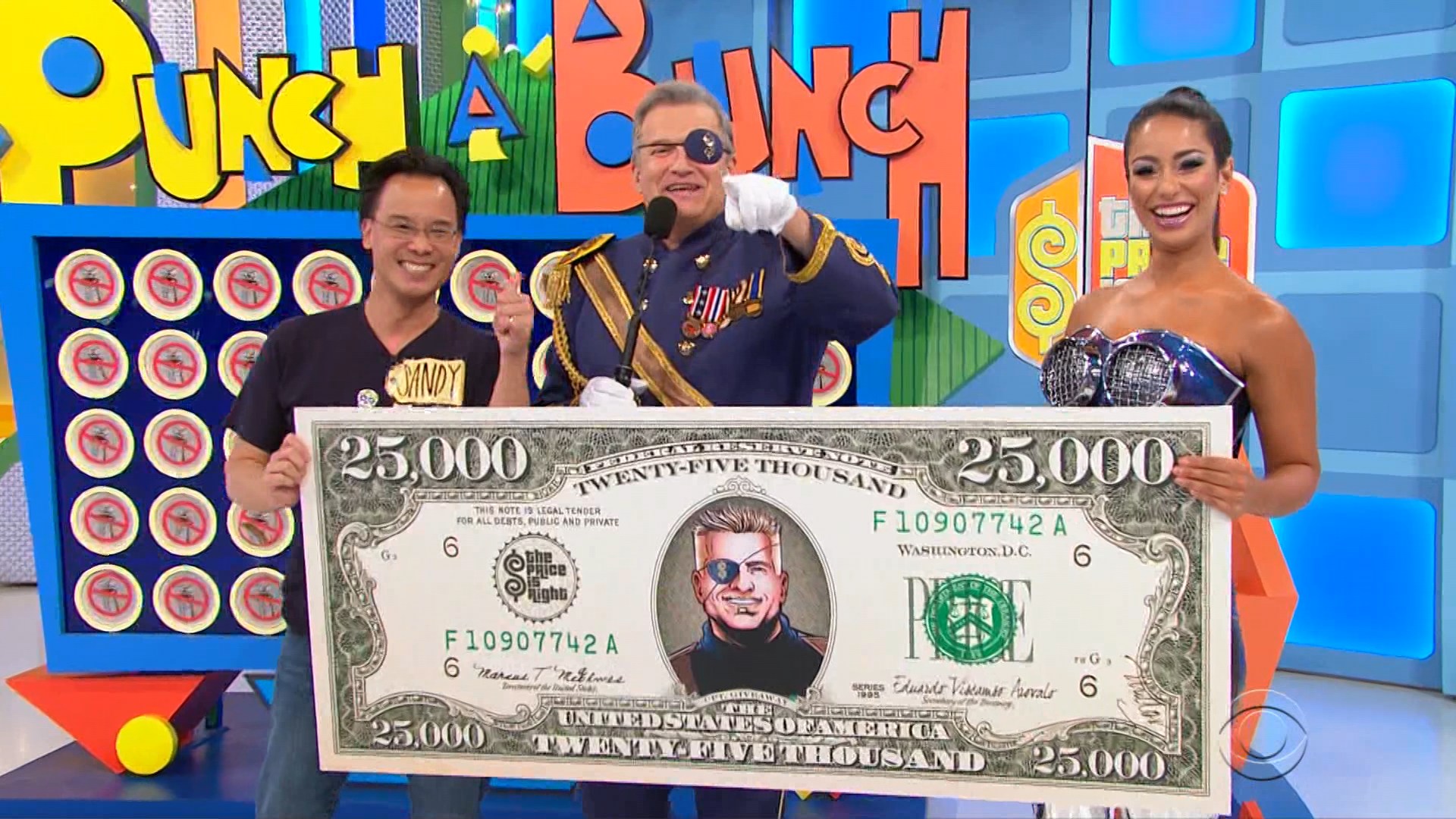 Drew Carey in an eye patch along with a contestant and model celebrate having given away $25,000 in Punch a Bunch.