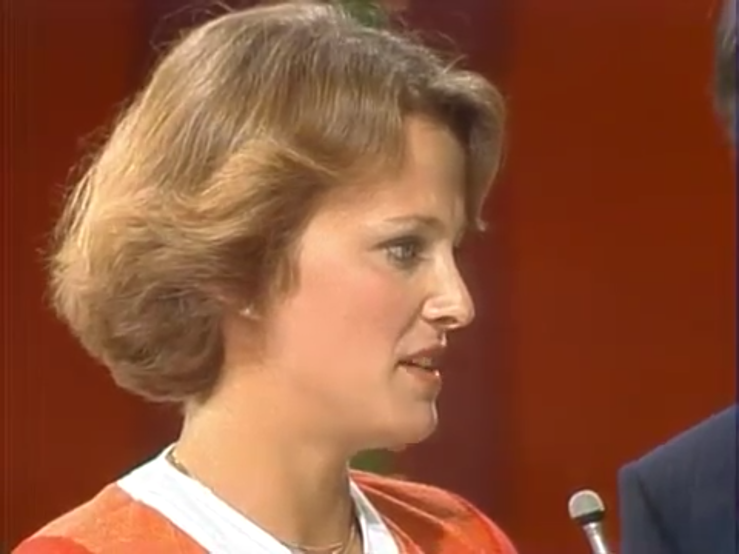 Close-up of a female contestant on The Price is Right, speaking intently while a male host stands beside her.