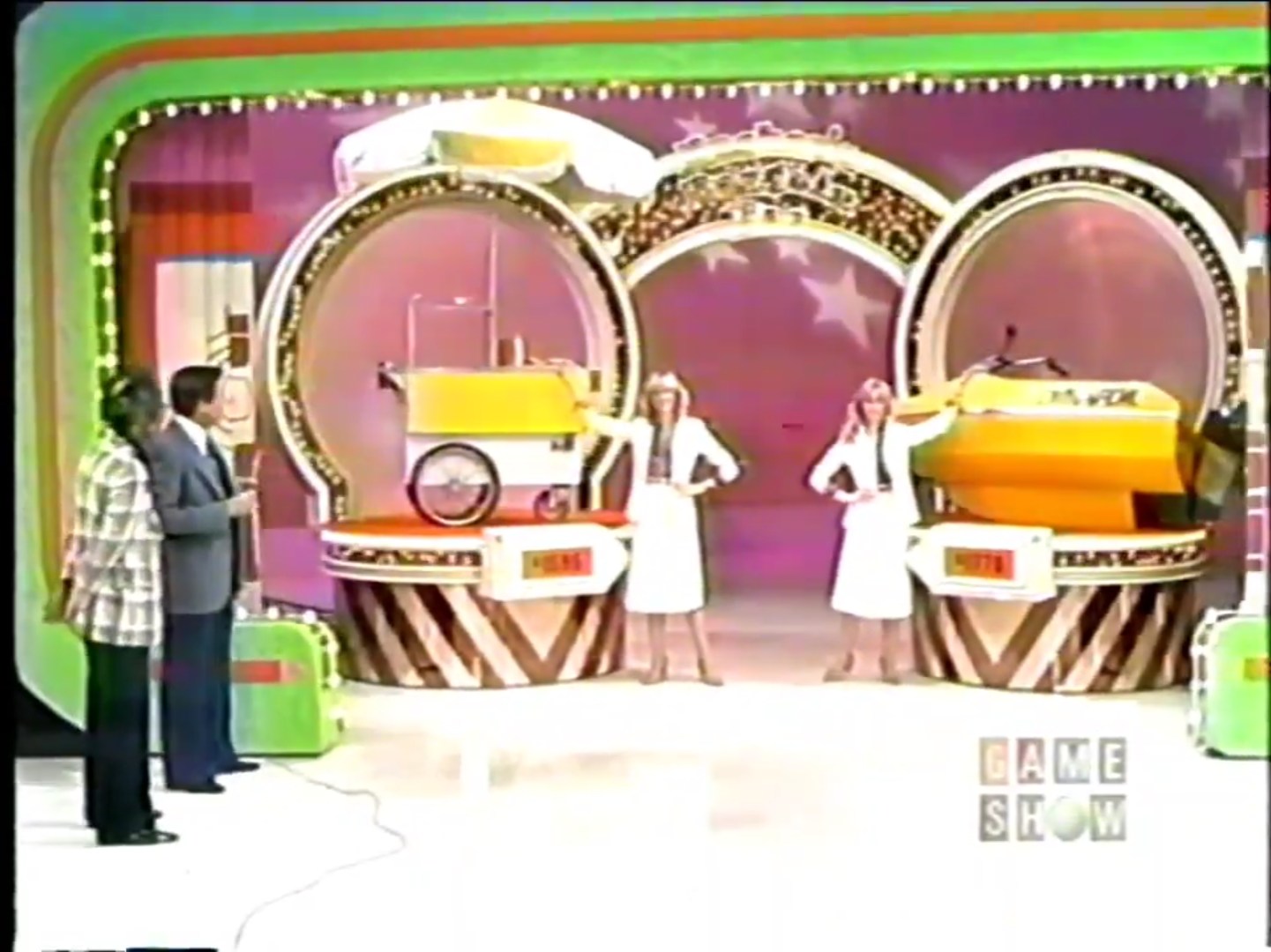 Two prizes displayed on a game show stage, featuring a hot dog cart on the left and a cycle boat on the right, with two hostesses presenting them.