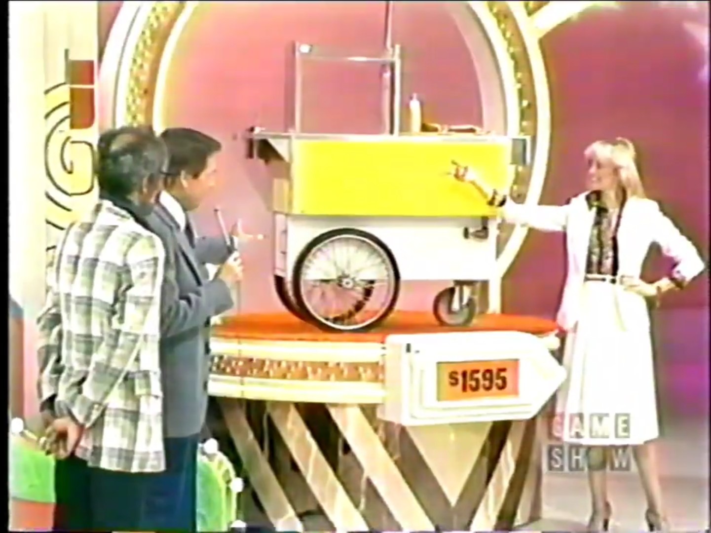 A hot dog cart displayed on a stage, with a price tag of 95. Contestants and a host are engaging in the game 'Bargain Game'.