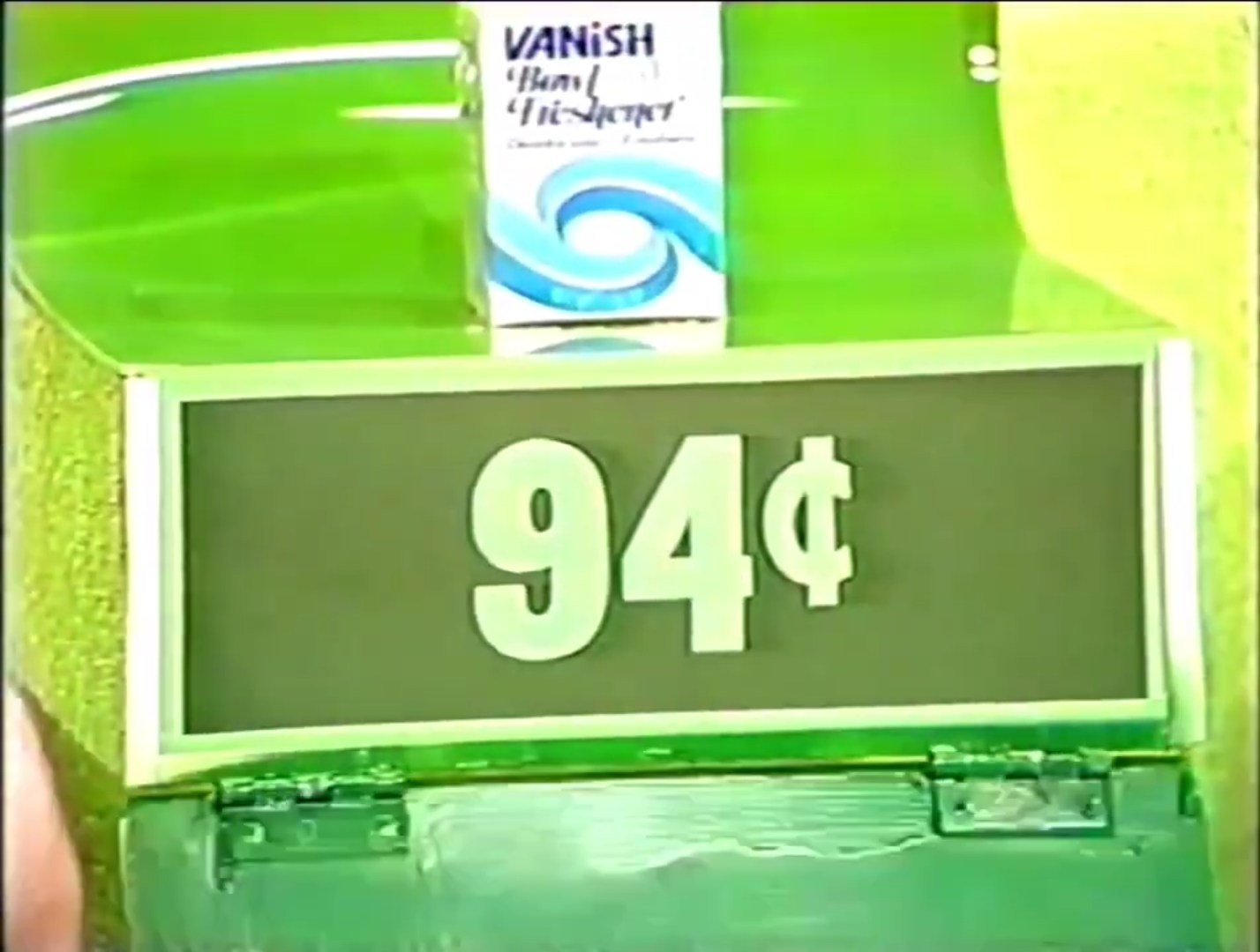 A display showing a price tag with '94¢' underneath a box of Vanish fabric refresher, set against a green background.