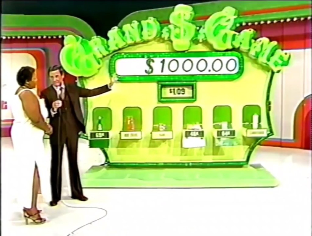 Contestant and host at the Grand Game on The Price is Right, with a prize total of $1,000 displayed and grocery items under a target price of $1.09.