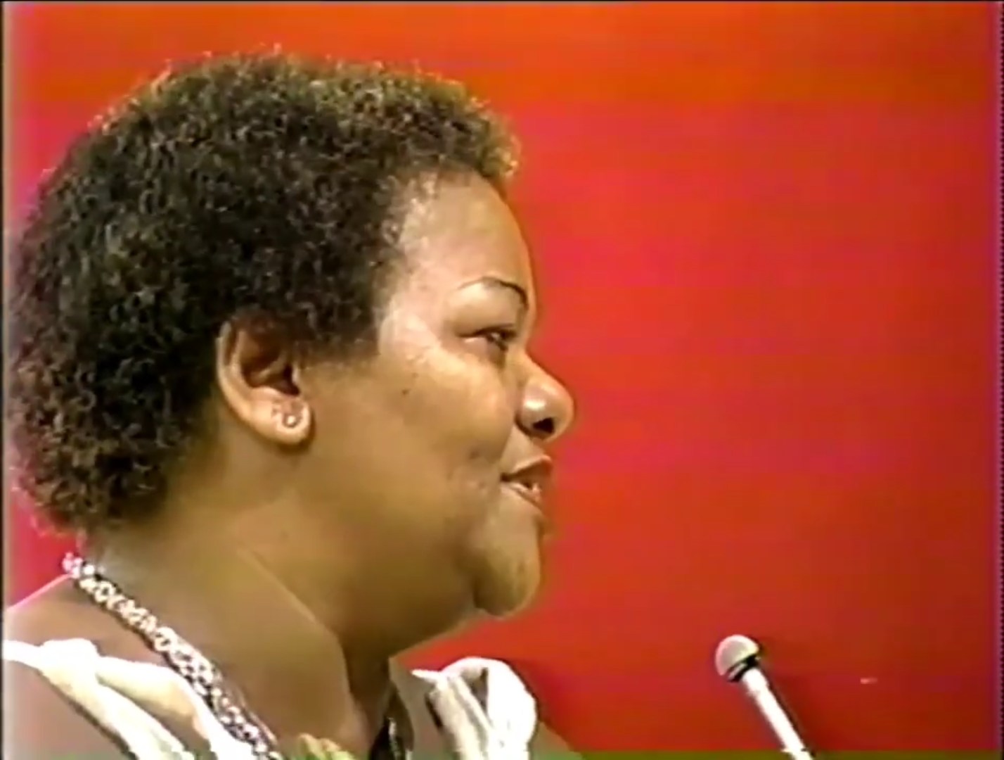 Close-up profile of a smiling contestant on a game show, with a colorful background.