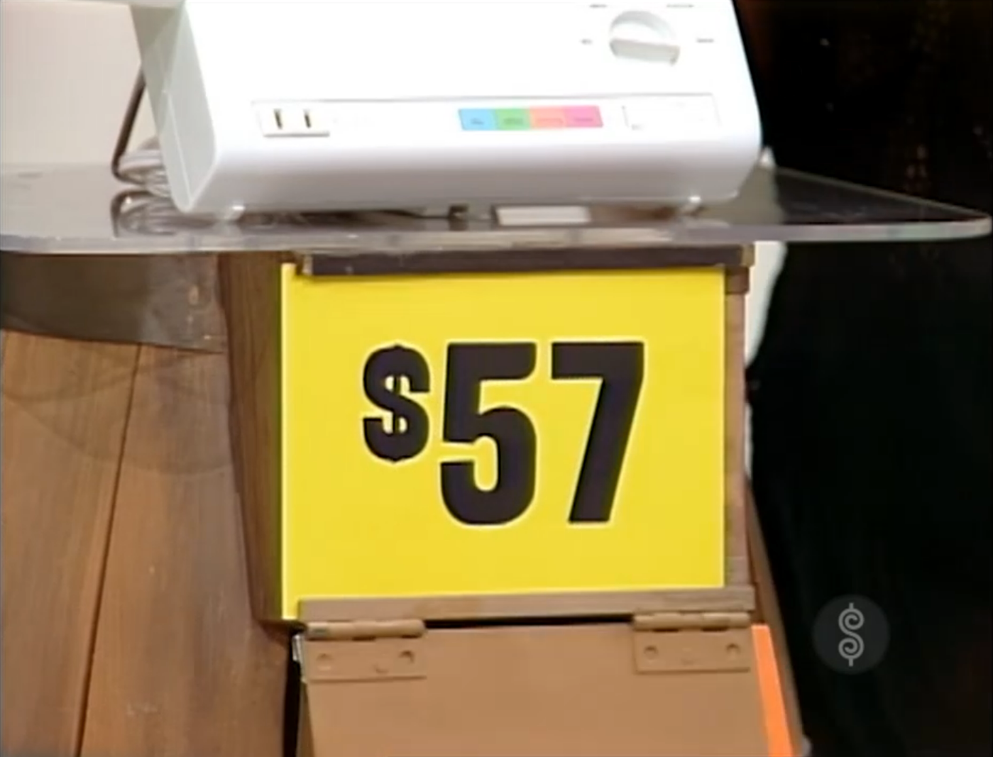A price tag displaying  next to a white appliance on a wooden counter.