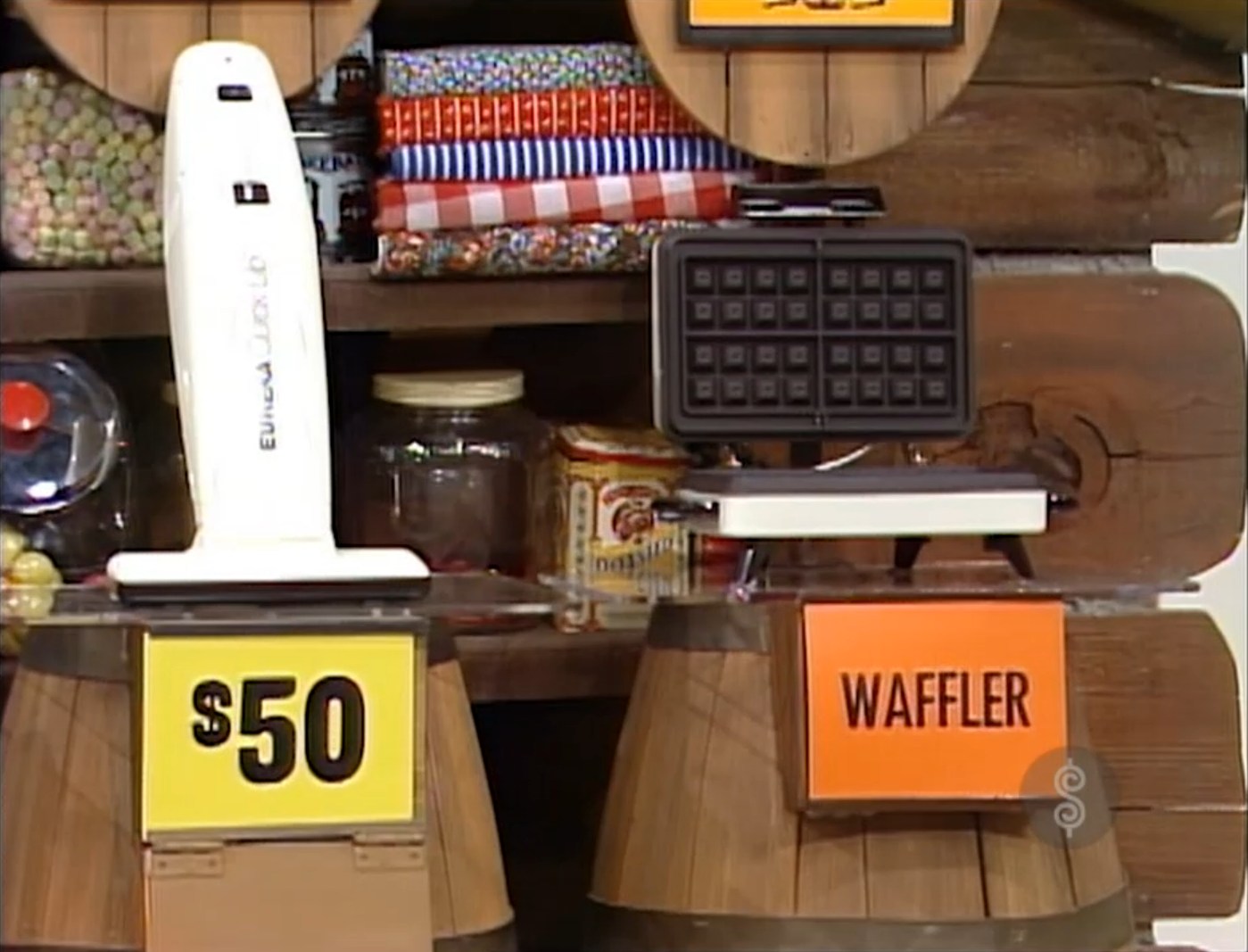 A  handheld vacuum cleaner displayed next to a waffler labeled 'WAFFLER' on a rustic wooden backdrop.