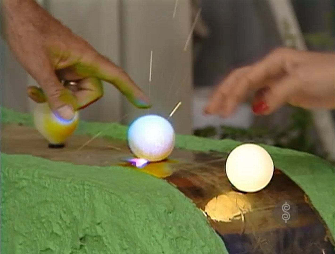 A hand reaching for a ping pong ball on a vibrant green surface, with sparks and light effects illustrating a motion.