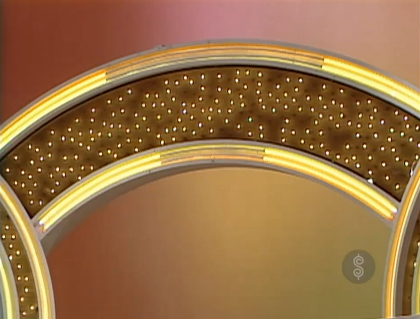 A close-up view of a bright, illuminated game show set featuring decorative lights and an orange background.