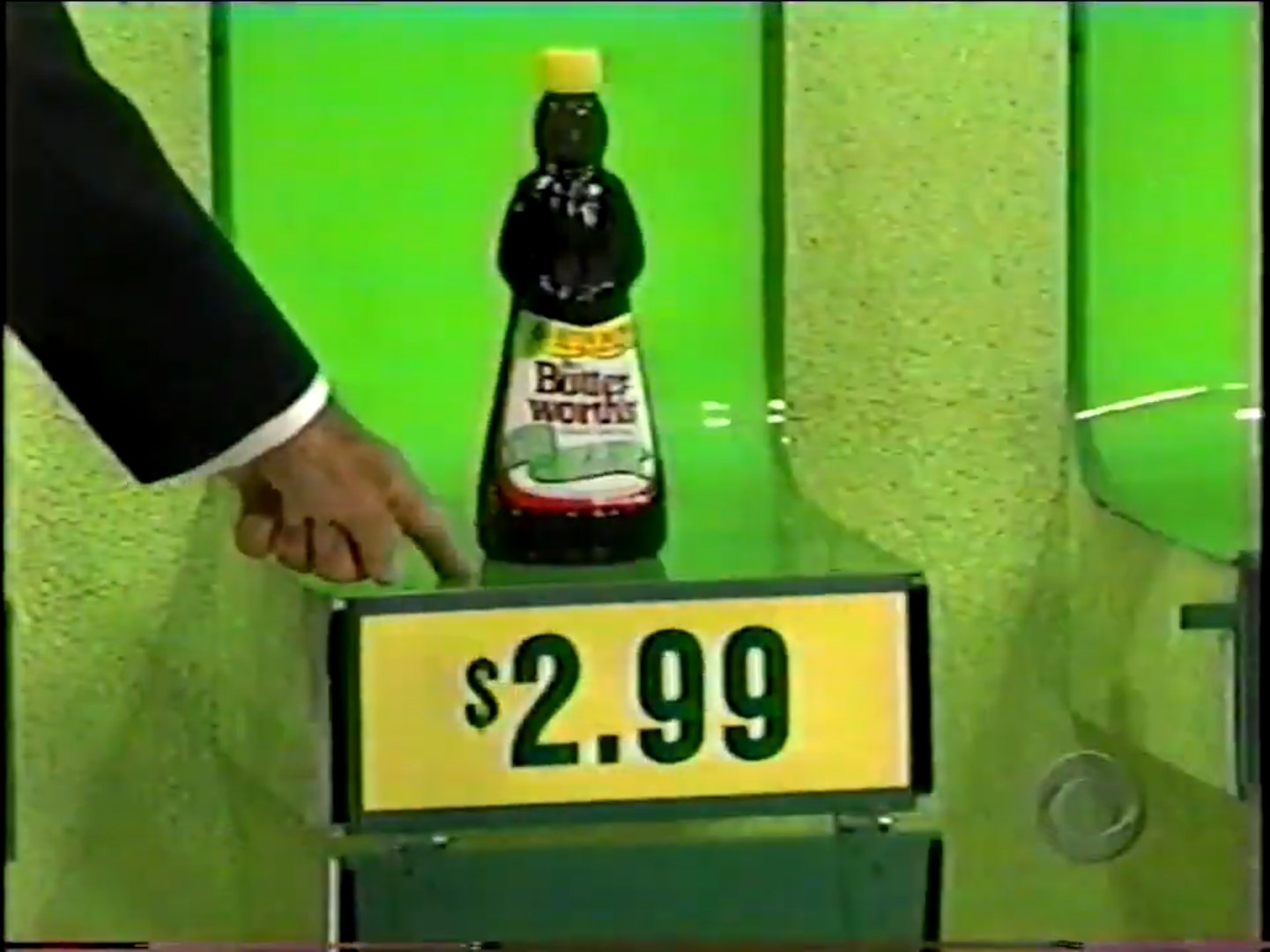 An outline of a hand pointing to a bottle of syrup priced at .99 on a green display board.