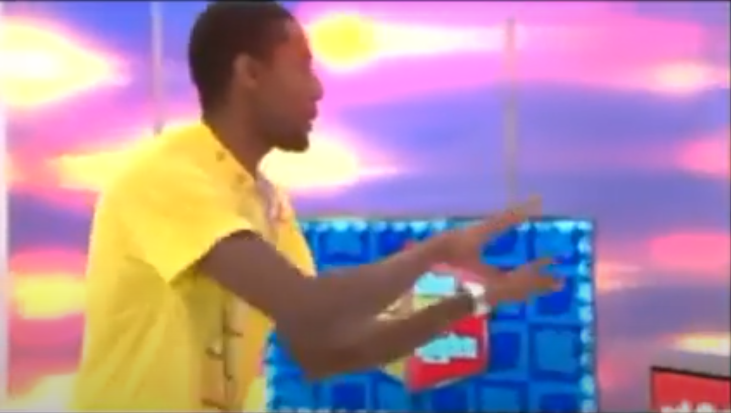 A contestant enthusiastically gestures while participating in the Bargain Game on a colorful game show set.