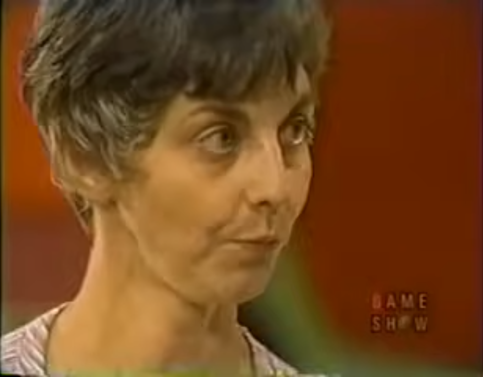 Close-up of a contestant on a game show, showing a focused expression as they participate in a dice game.