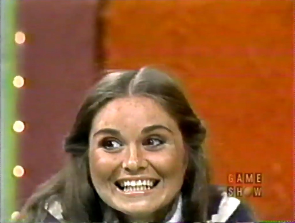 A contestant on a game show with a big smile, showcasing excitement or enthusiasm.