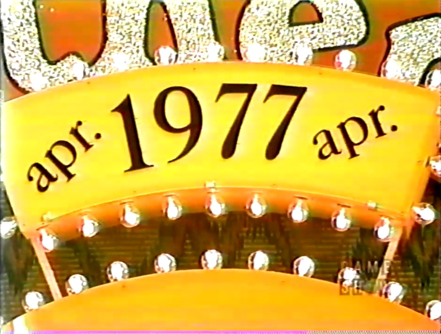 Close-up of a game show sign displaying the date 'april 1977' in bold letters.