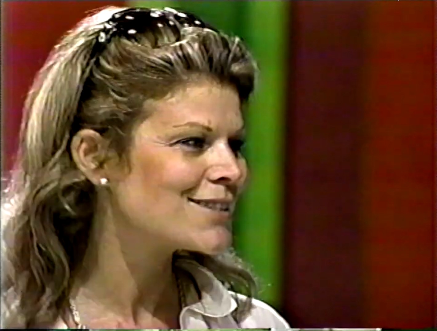 A contestant smiles while participating in the pricing game 'Hit Me' on The Price is Right, with a colorful background.