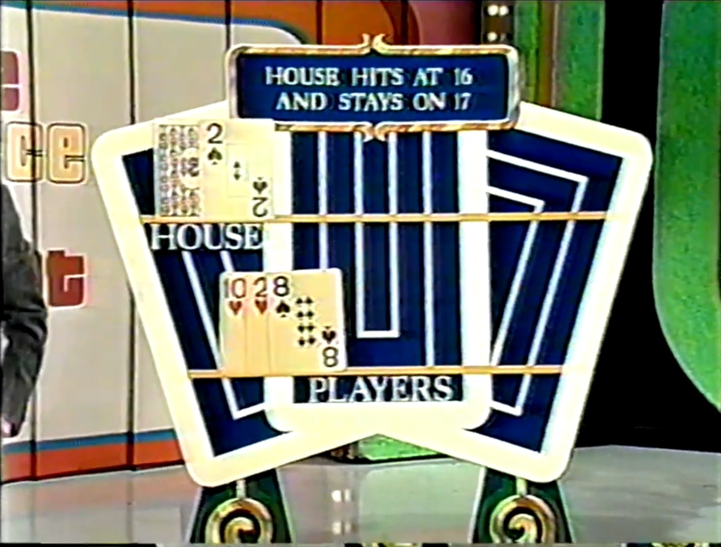 The display screen from the game 'Hit Me' showing the current status of the house hand with a 2, and the player's hand with a 10, a 2, and an 8, indicating the house hits at 16 and stays on 17.