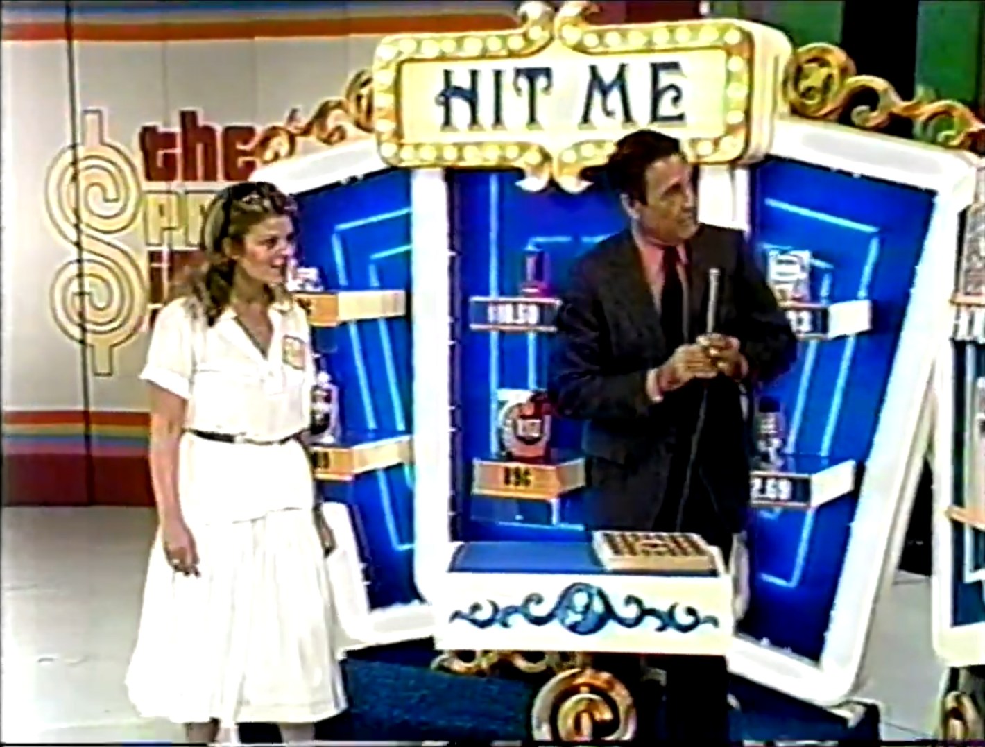 A contestant plays the 'Hit Me' game on The Price Is Right, standing beside a host. The game features a colorful backdrop with various products and prices, as the contestant prepares to make a choice.