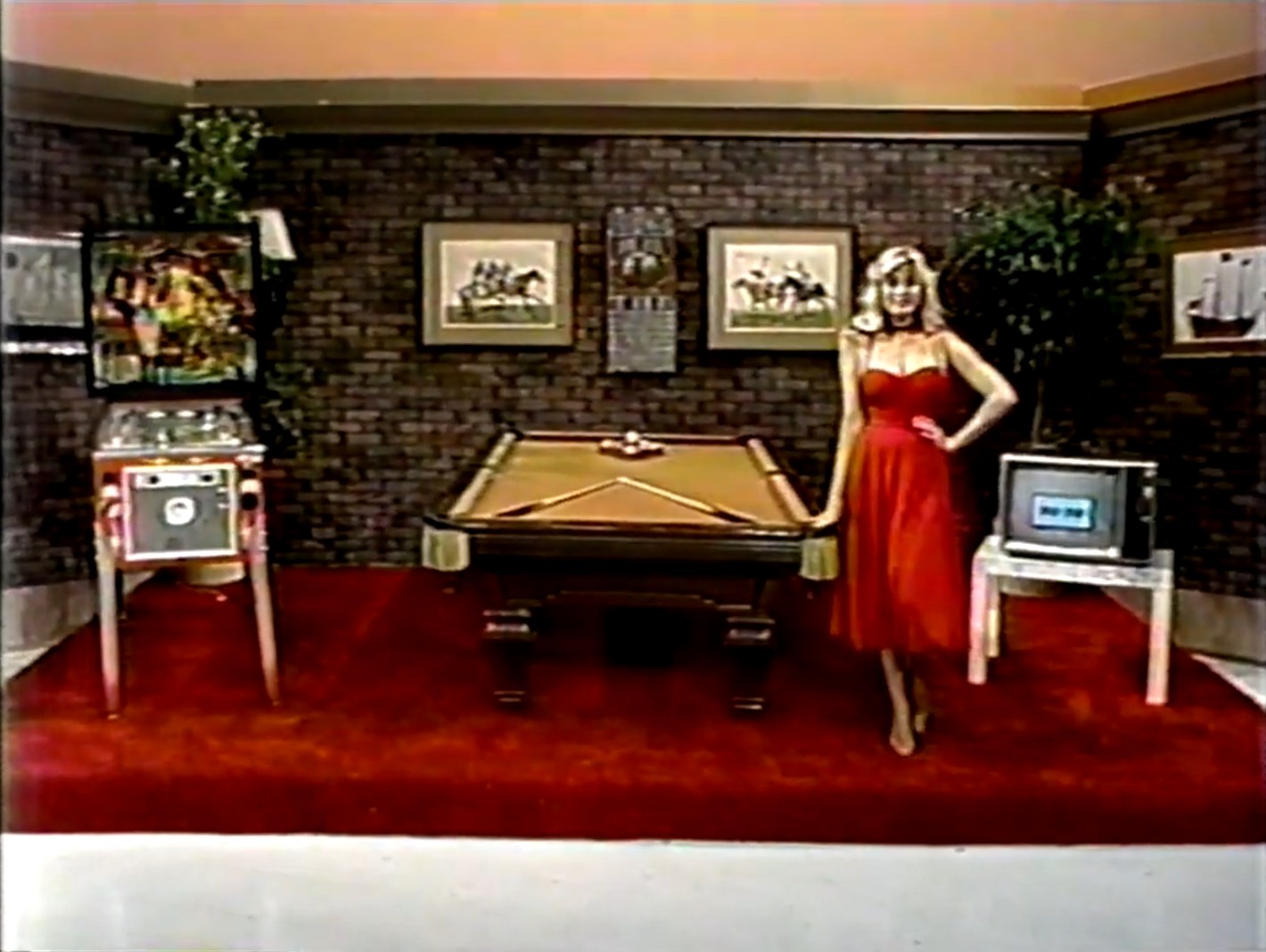 A woman in a red dress poses next to a pool table in a game room setting, featuring a pinball machine and an old television displaying 'Gold Star'.
