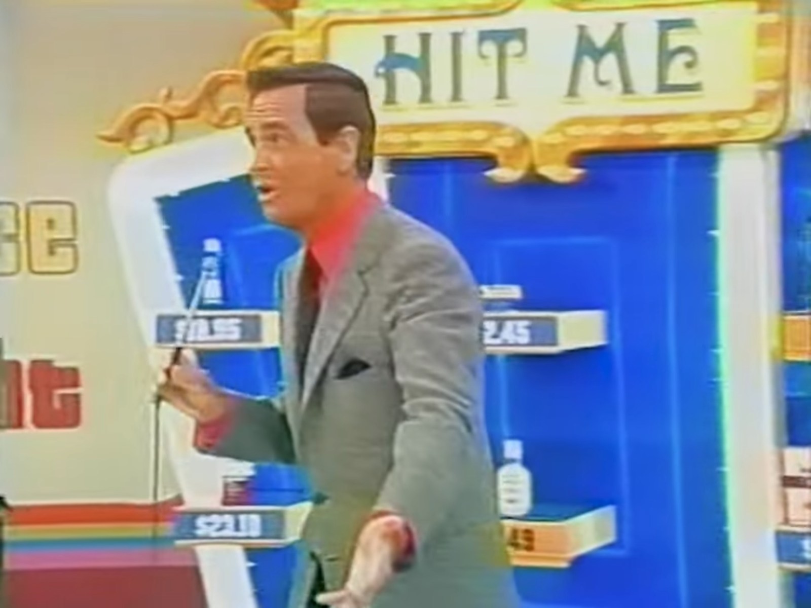 Bob Barker explaining the pricing game 'Hit Me' on the set of The Price is Right, with product prices displayed in the background.