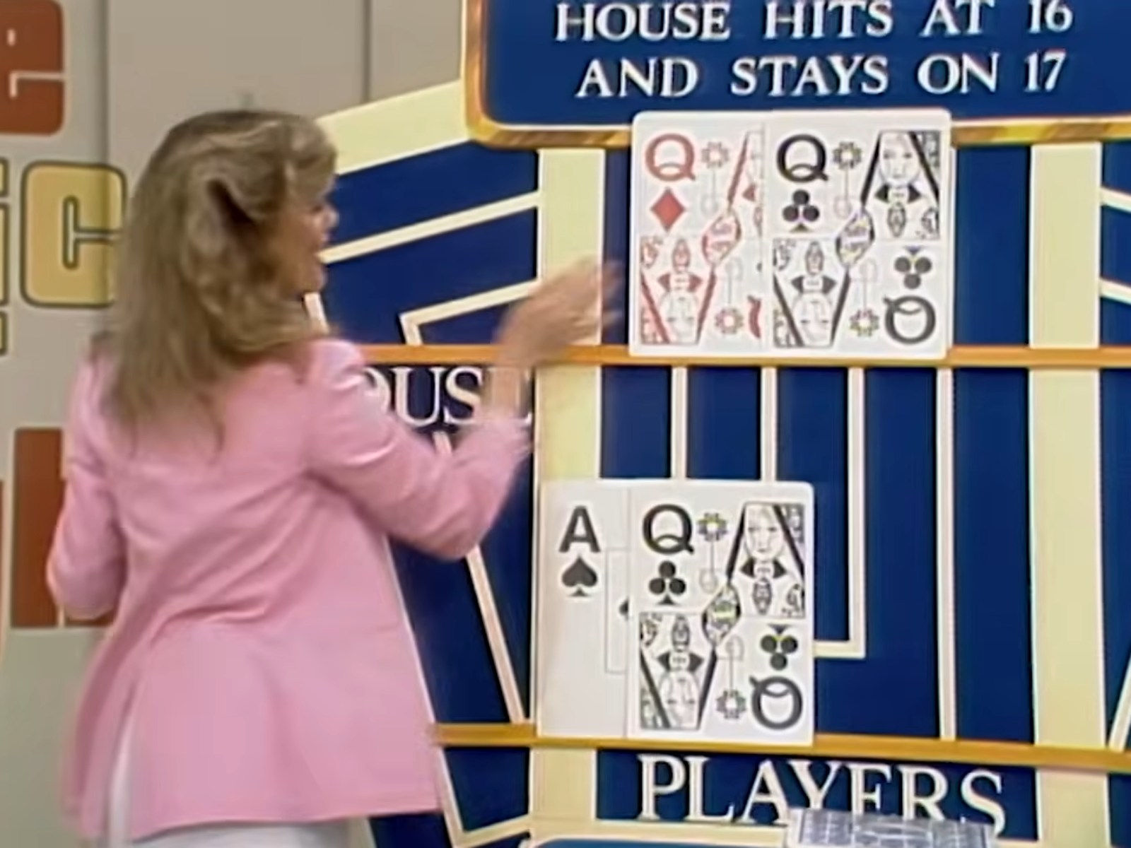 A game show contestant reveals the house's hand in a pricing game called 'Hit Me', featuring playing cards displayed on a board.
