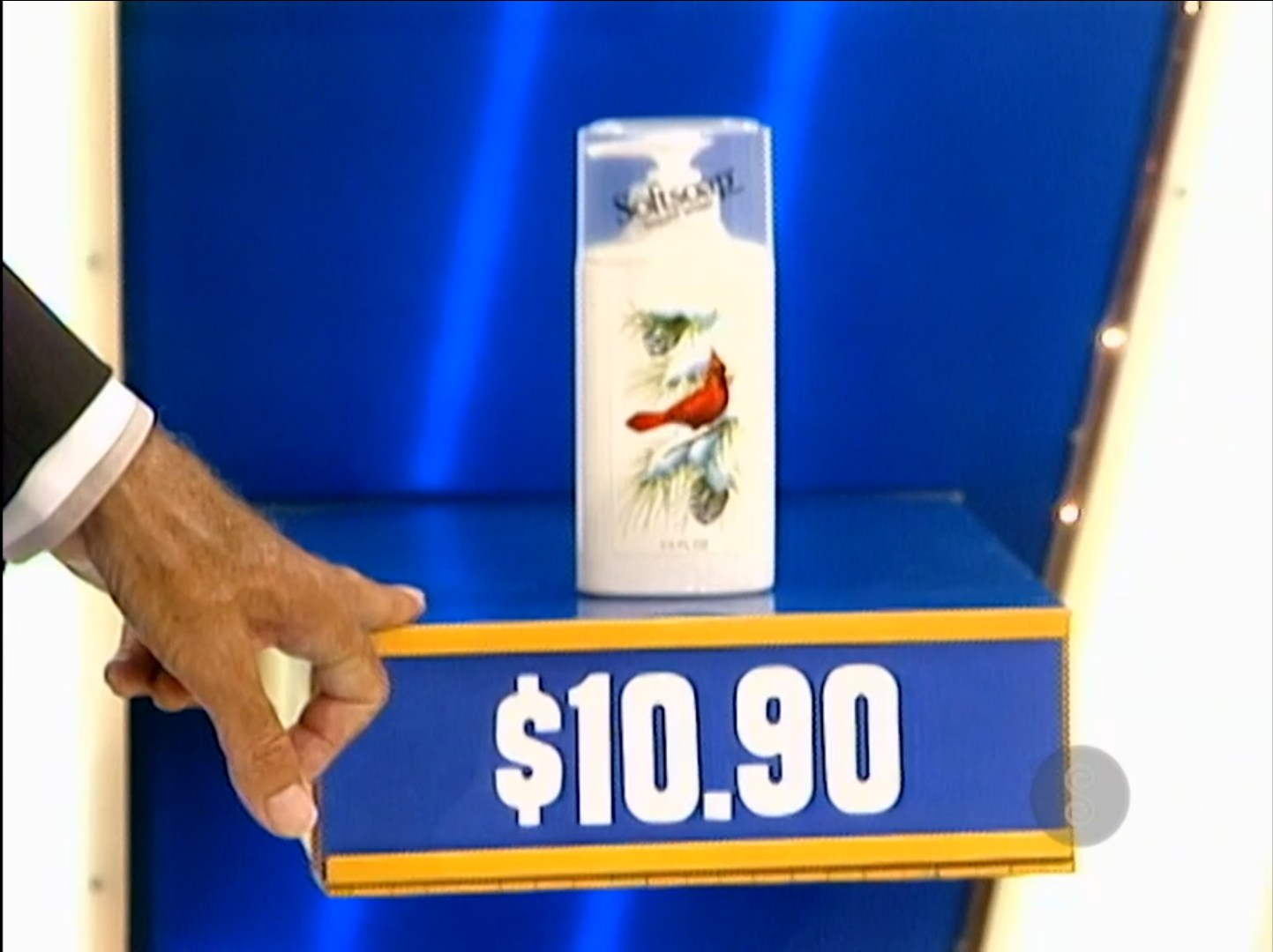 A hand holding a price tag displaying .90 next to a decorative bottle featuring a cardinal bird design.