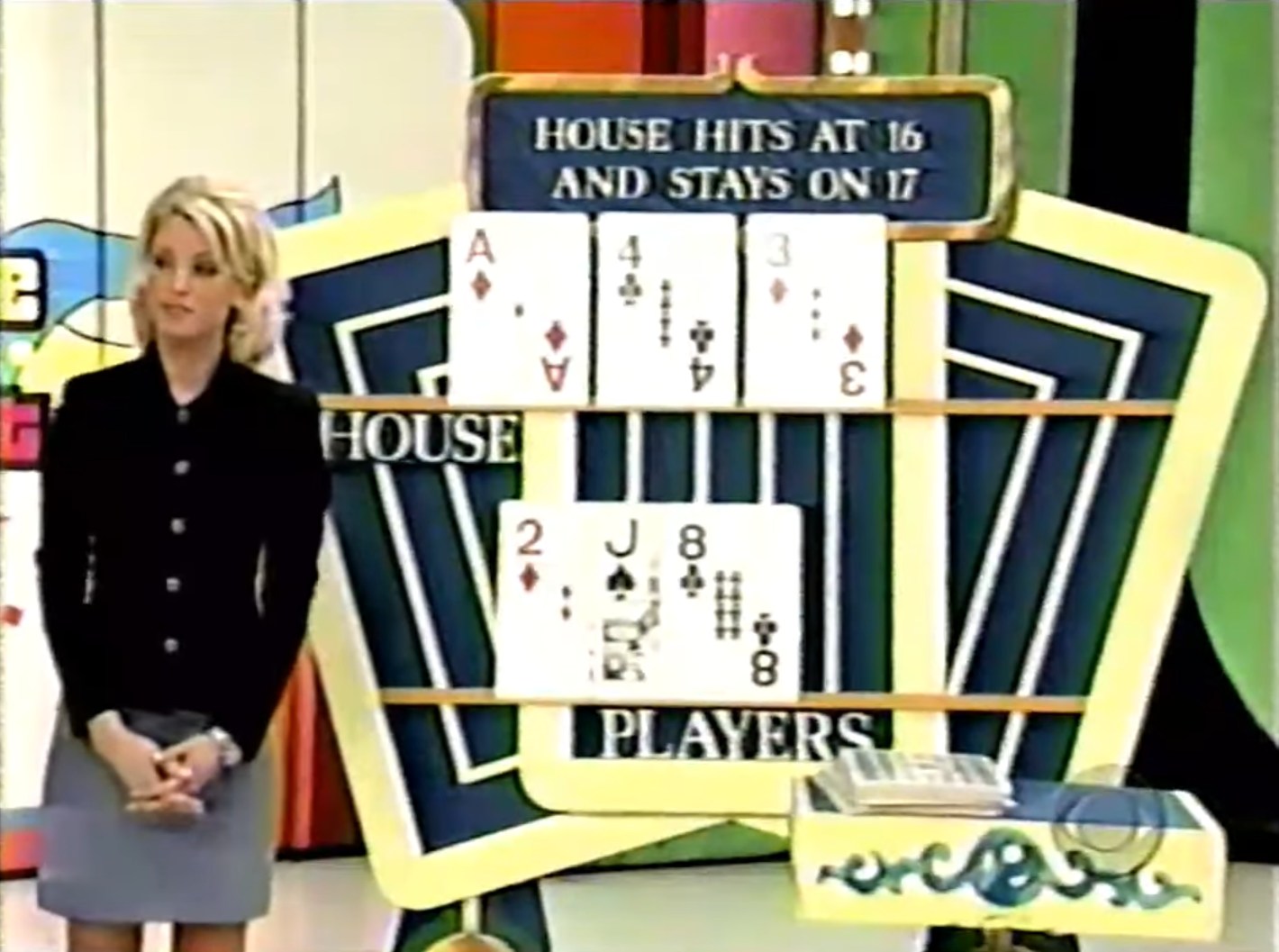 A model standing next to a card display showing the house's hand with an Ace, 4, and 3, while the player's hand shows a 2, Jack, and 8.