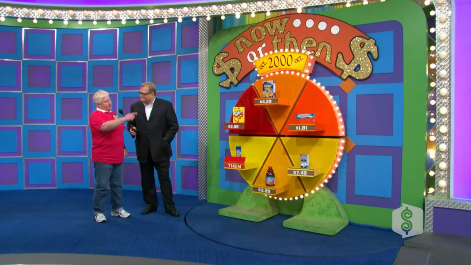 A contestant wearing a red shirt interacts with Drew Carey on a Price is Right game show set, showcasing a circular game board titled 'now or then' with grocery product prices labeled for guessing.