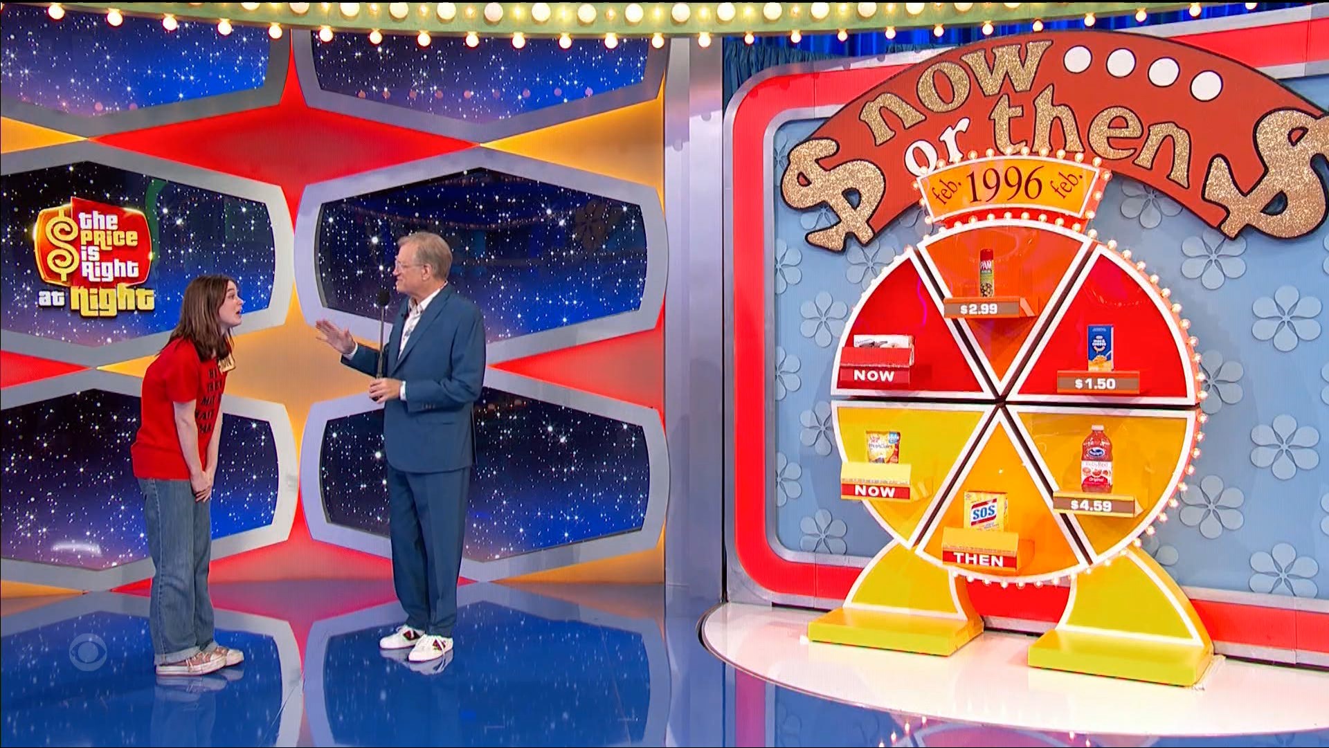 Contestant engaging with host on 'Now or Then' game show set, with a wheel displaying grocery prices for 'NOW' and 'THEN'.
