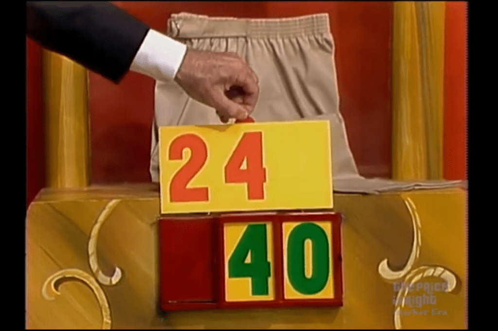 A hand is holding a yellow card displaying the number '24' and a green card displaying the number '40', with a pair of shorts in the background.
