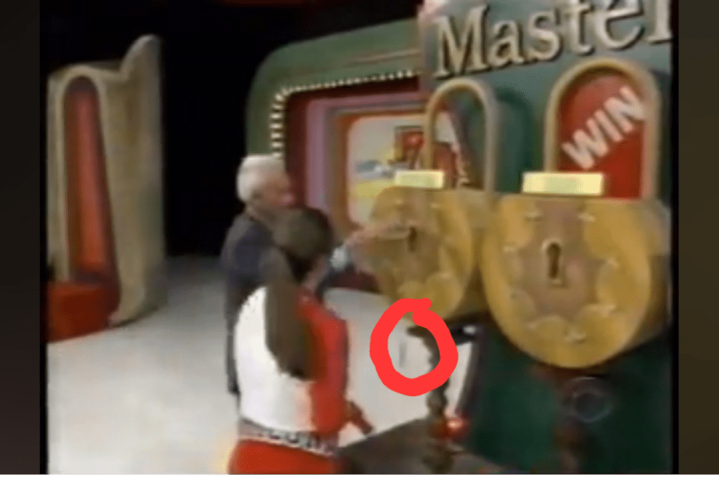A scene from the Master Key game on The Price is Right, featuring a host and a contestant interacting with a board displaying locks and prize options.