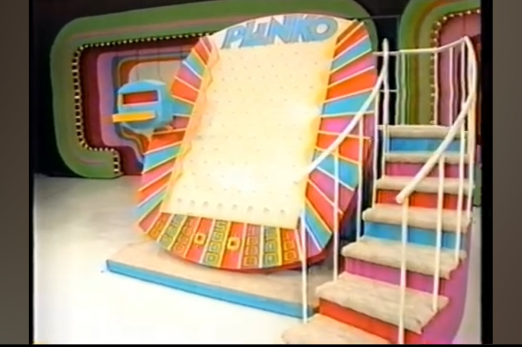 A colorful Plinko board with a sloped surface and pegs, along with stairs leading up to it, set against a vibrant backdrop.