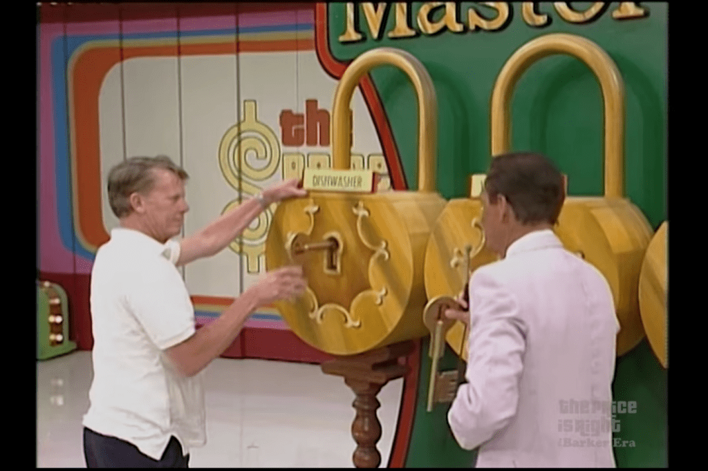 Contestants interacting with a large display of locks in the game Master Key on The Price is Right.