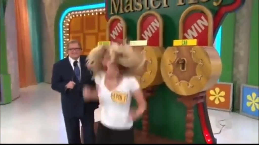 A contestant is excitedly jumping in front of the Master Key game stage, featuring two large locks labeled with prizes. Host Drew Carey smiles beside her.