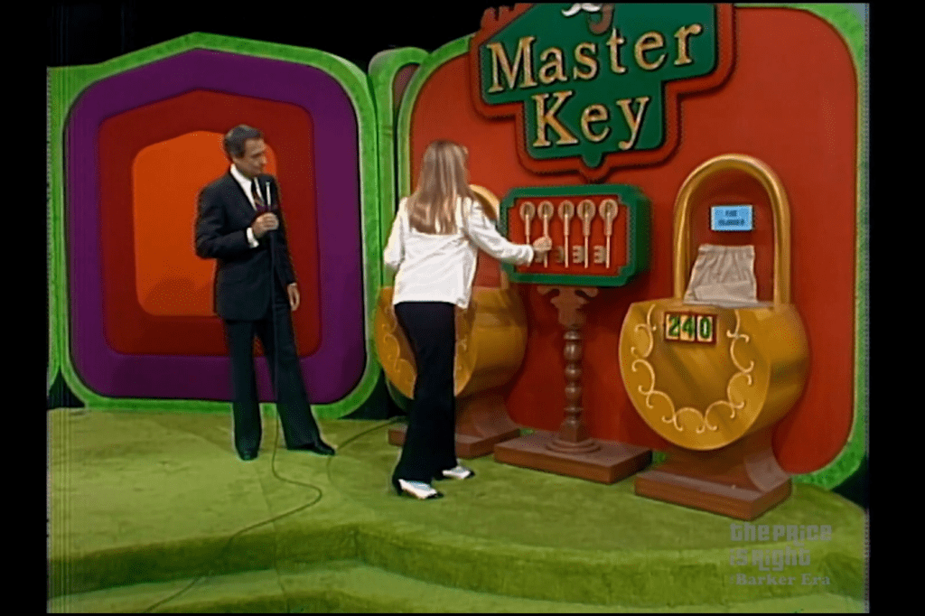 A contestant interacts with a display for the game 'Master Key' while a host holds a microphone, with colorful backgrounds and two lock containers visible.
