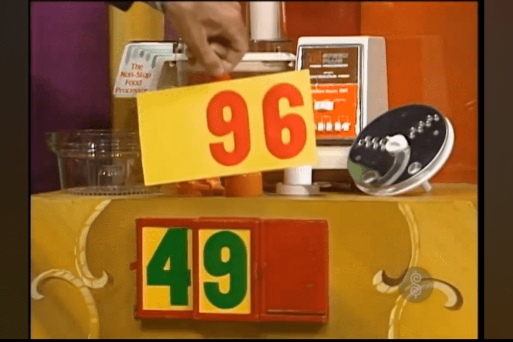 A colorful display showing the price of a kitchen appliance with the numbers 96 and 49, along with a food processor in the background.