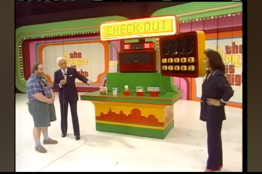 A scene from The Price is Right featuring the CHECK-OUT game setup, with a male contestant, the host, and a female model presenting the grocery items.