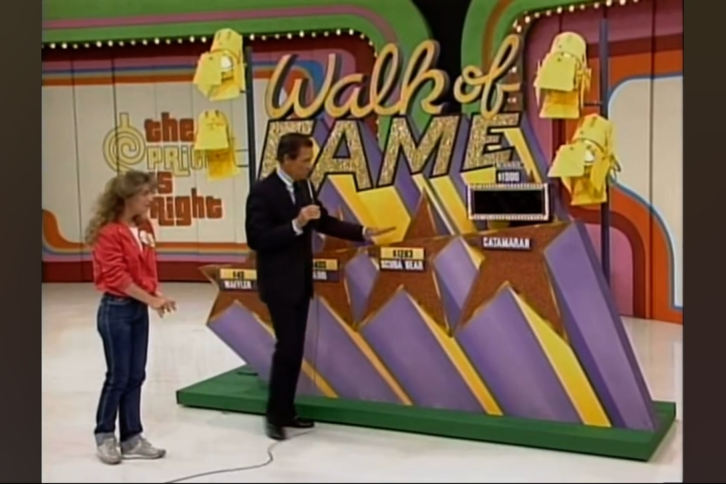 A contestant stands in front of the 'Walk of Fame' game display on a television game show, with a host explaining the prizes.