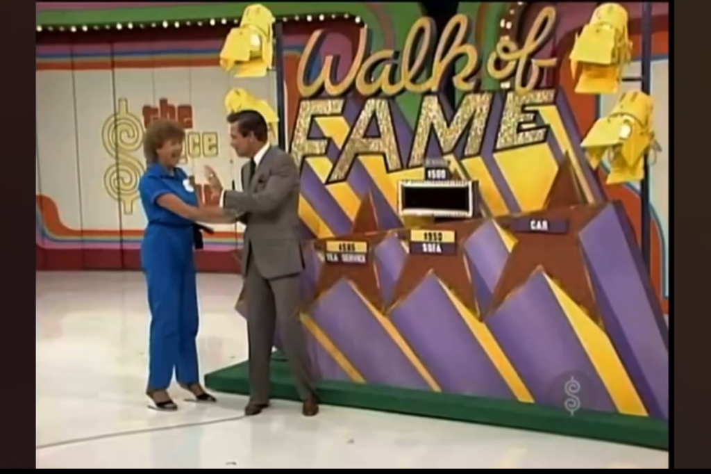 Contestant and host interacting in the 'Walk of Fame' game show segment, with the game board visible in the background.
