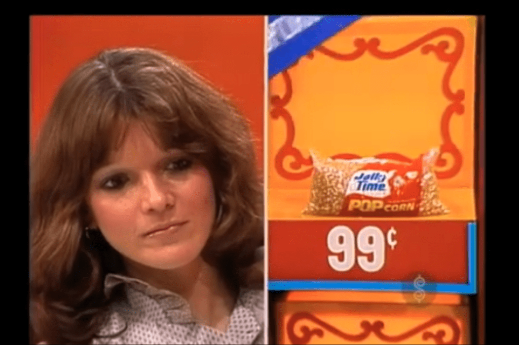Contestant contemplating her choice while focusing on a package of Jolly Time popcorn priced at 99 cents.