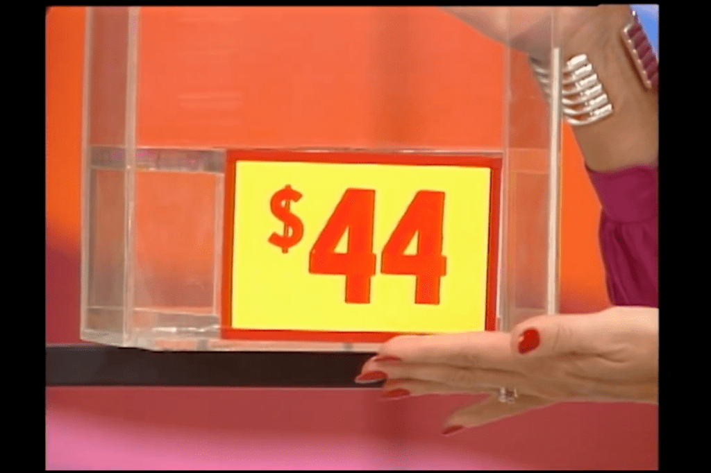 A hand holding a sign displaying the price , positioned in front of a colorful backdrop.