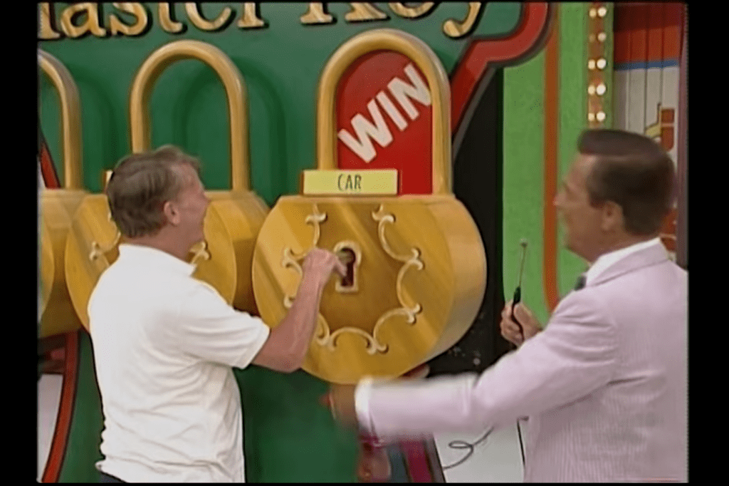 Contestant attempting to unlock a prize lock on the Master Key game show with host reacting positively.