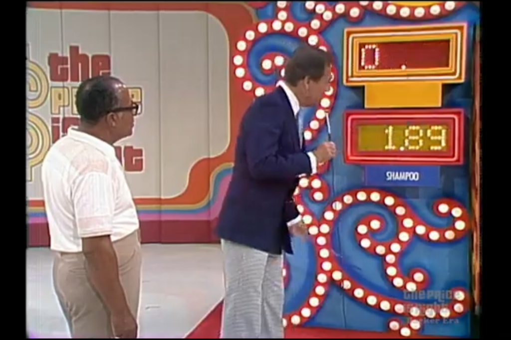 A contestant and the host stand in front of a game board displaying a price of .89 for shampoo, while another display shows '0.'