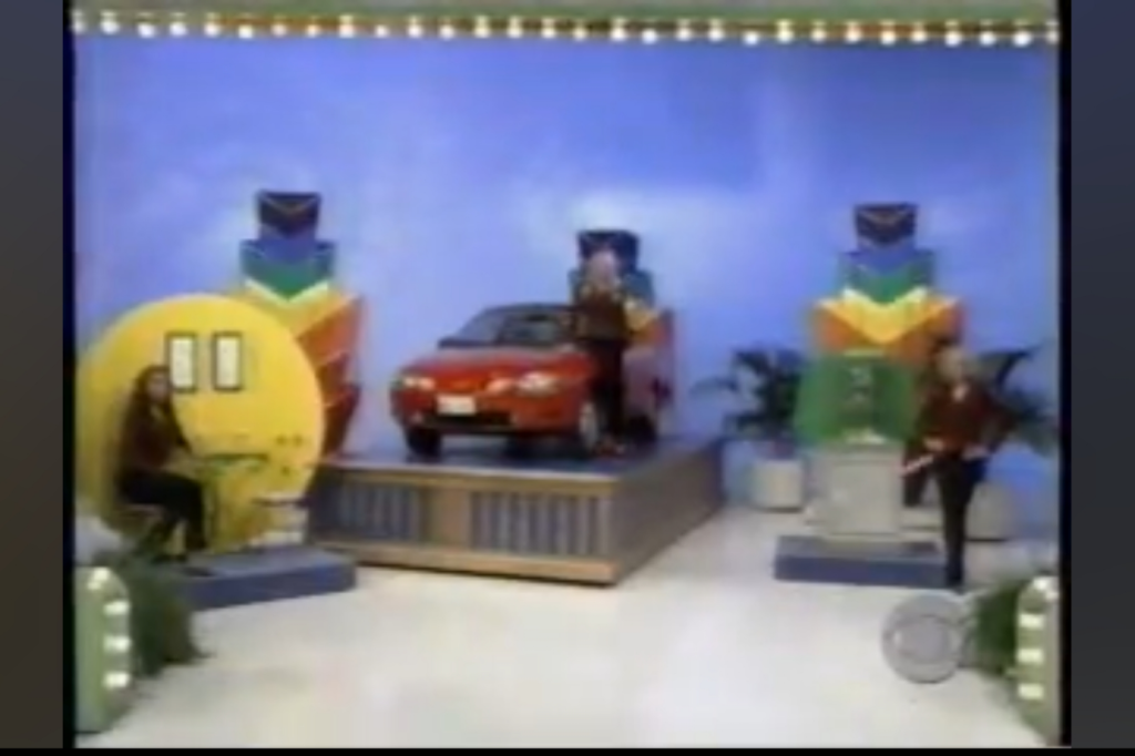 A contestant playing the Master Key game on a colorful stage with a red car displayed prominently.