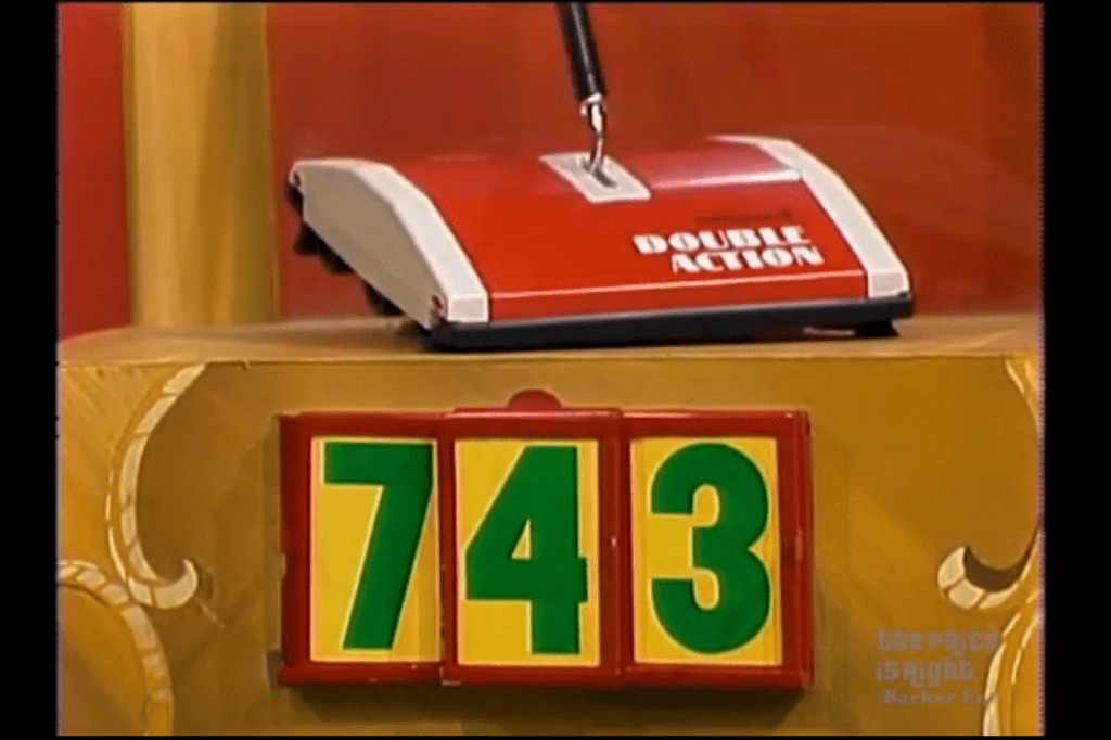 A red double action sweeper placed on a game stage, with the displayed prices '743'in green and yellow.