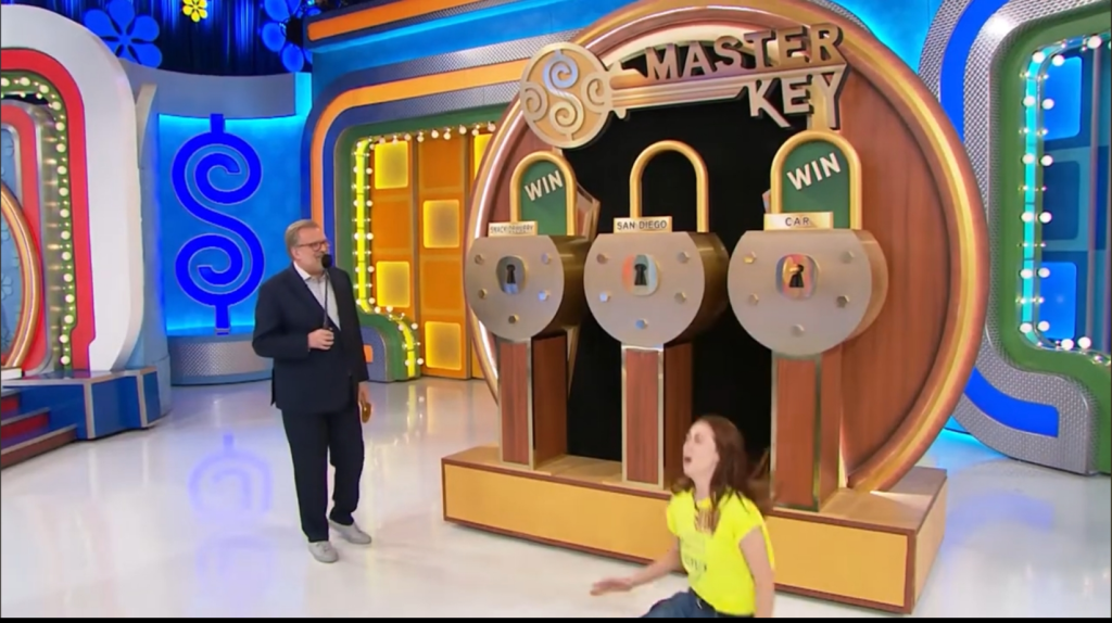 A contestant celebrating on stage of the game 'Master Key' with three locks representing prizes, including a car and a trip to San Diego.