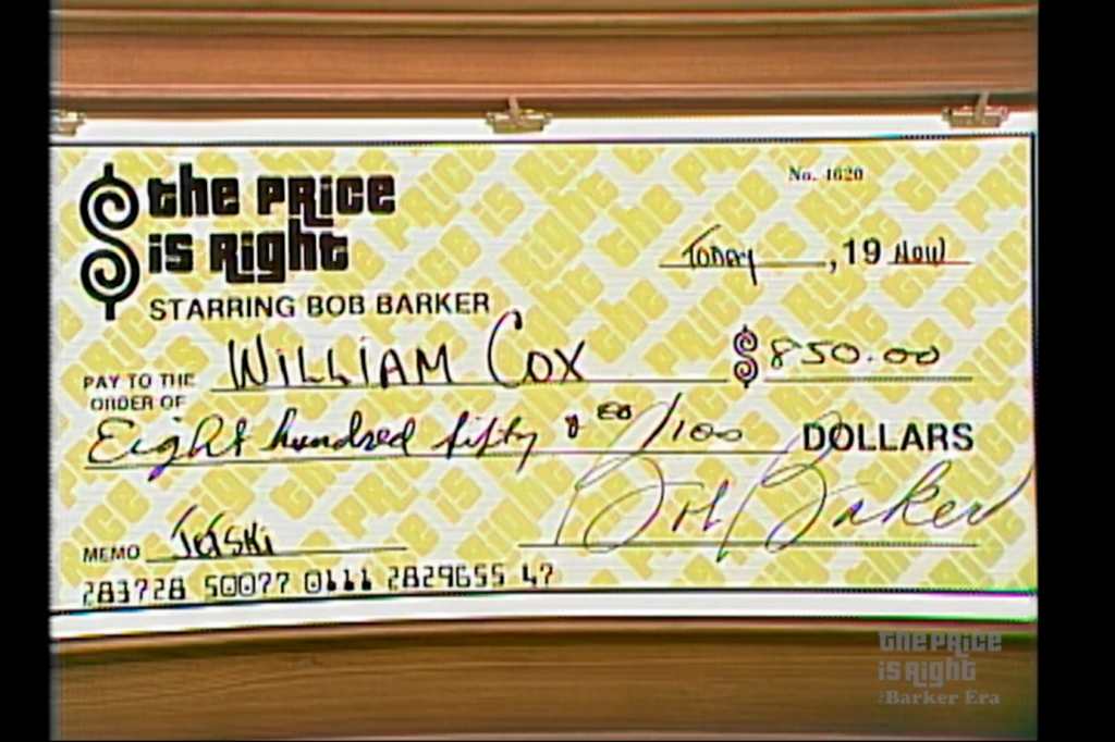 A large novelty check from 'The Price is Right,' made out to William Cox for 0.00, featuring a yellow background with the show's logo and Bob Barker's signature.